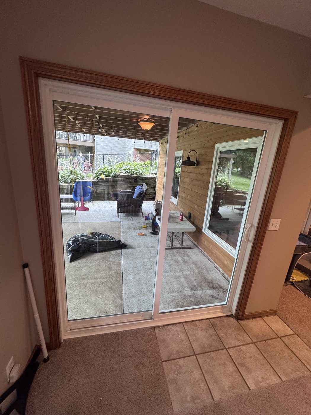 The new white vinyl sliding patio door from inside the basement playroom — clean lines, clear Low-E glass, wide view of the patio